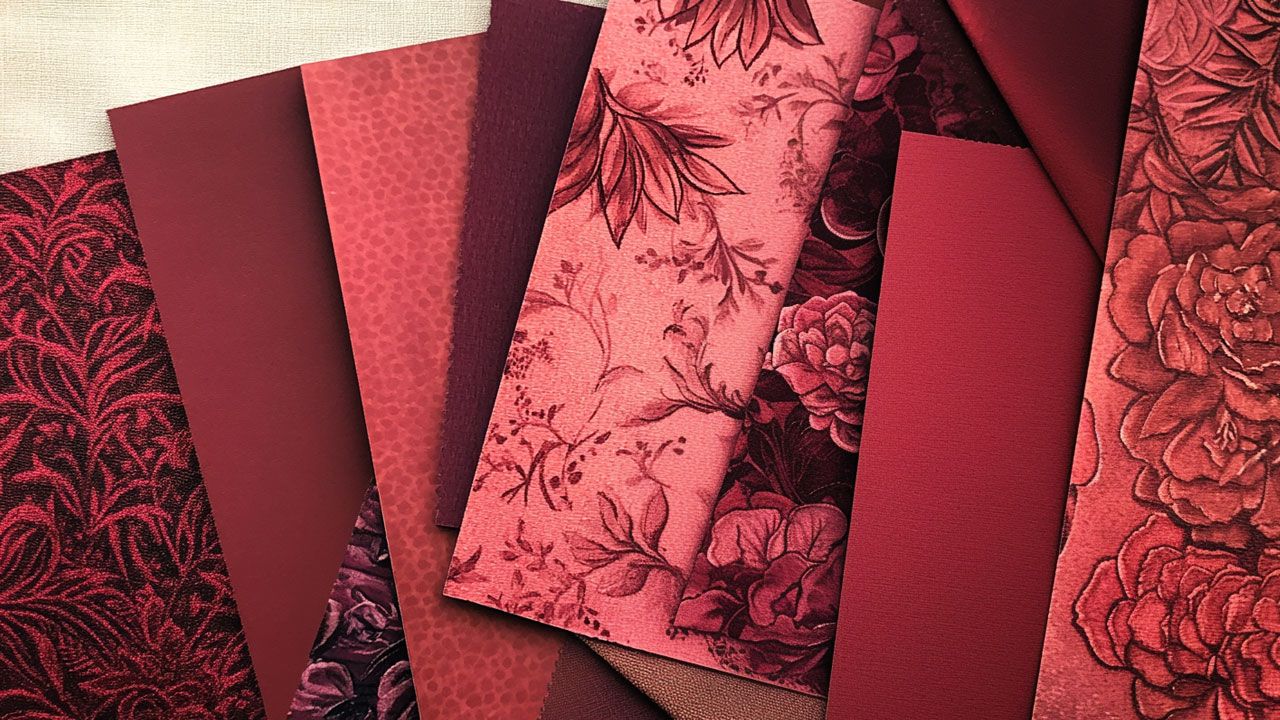 A collection of red and pink patterned fabric swatches with floral and geometric designs arranged in an overlapping display.