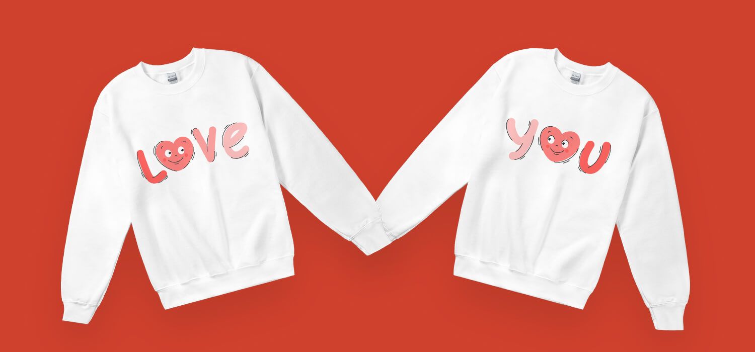 Two white sweatshirts with "LOVE" and "YOU" in pink letters, featuring heart-shaped 'O's, displayed on a red background.