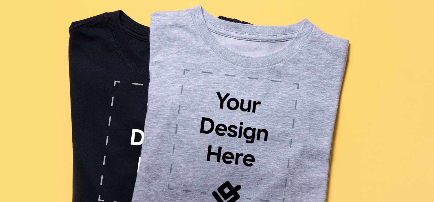 Two t-shirts on a yellow background, one black and one gray, both featuring the text "Your Design Here" in bold, black letters.