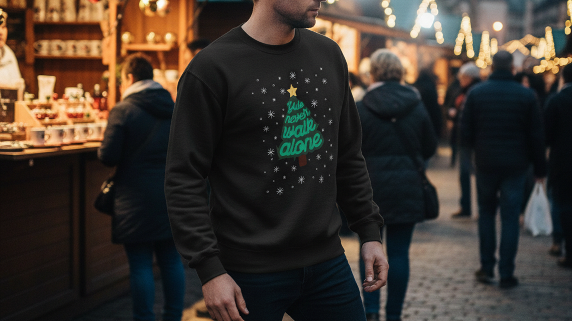 Man in festive sweater at a holiday market, with blurred people and lights in the background, creating a warm, seasonal atmosphere.