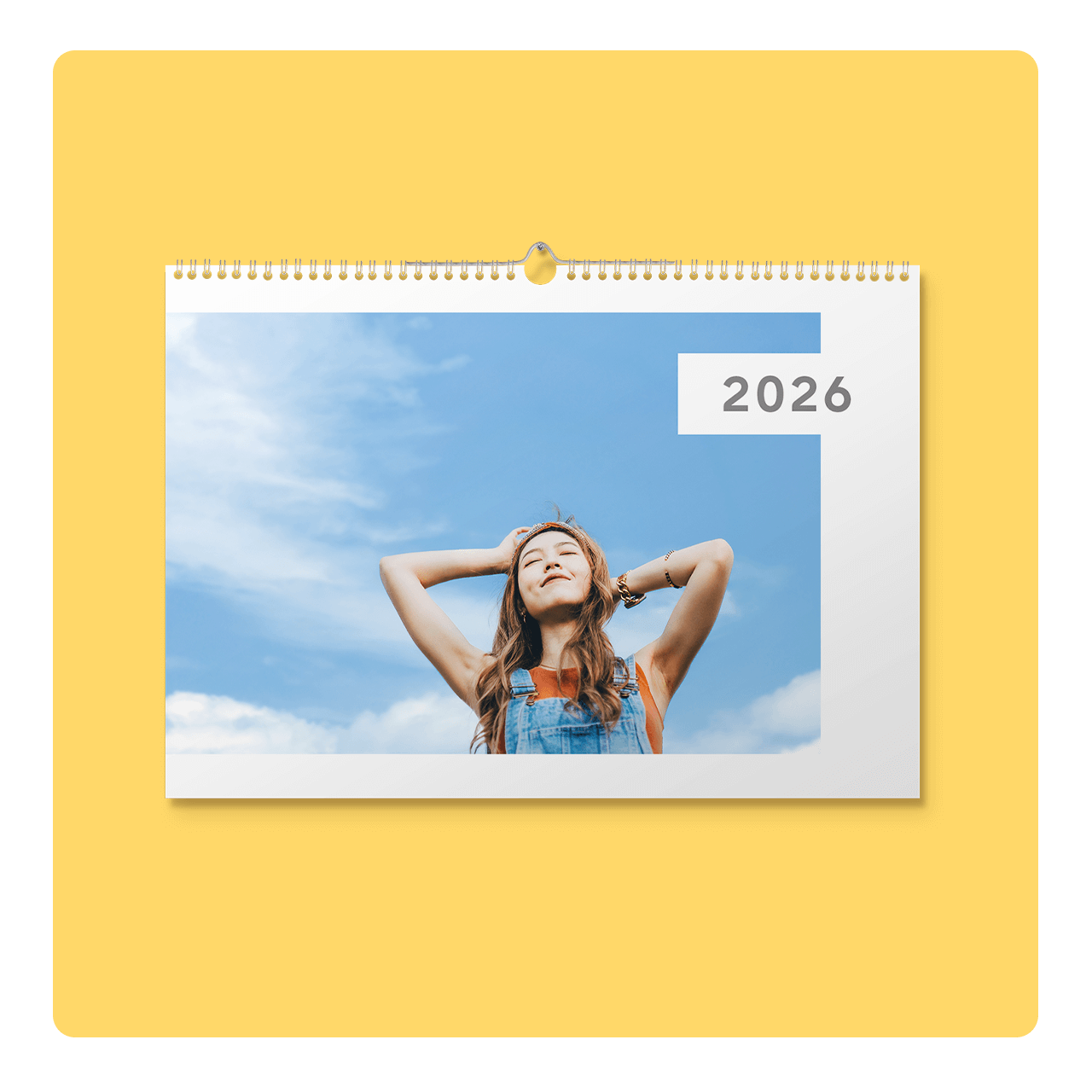 Calendar page for 2026 featuring a woman in overalls smiling with eyes closed against a blue sky background.